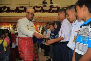 Wakil Bupati Mamuju H. Irwan SP Pababari saat memberikan secara simbolis seragam sekolah gratis kepada siswa